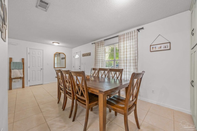 dining room with light tile patterned floors, a textured ceiling, baseboards, and visible vents