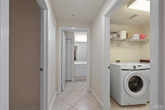 laundry room with light tile patterned floors, a textured ceiling, and washer / clothes dryer