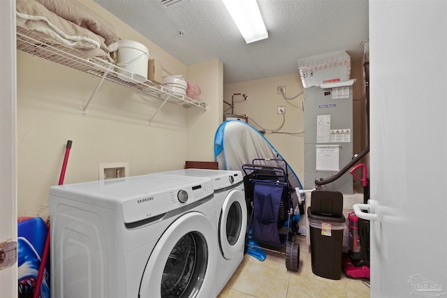 clothes washing area with a textured ceiling, washing machine and dryer, and light tile patterned floors