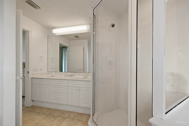 bathroom with tile patterned flooring, vanity, a textured ceiling, and walk in shower