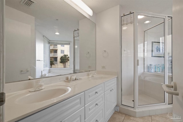 bathroom with tile patterned floors, a shower with door, vanity, and a textured ceiling