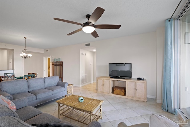 living room with a textured ceiling, ceiling fan with notable chandelier, and light tile patterned flooring