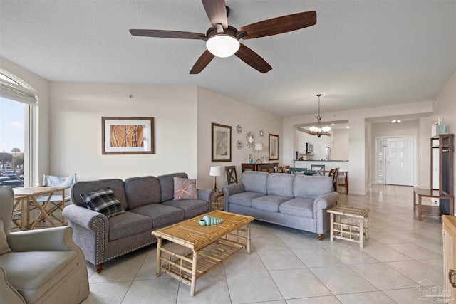 living room with ceiling fan with notable chandelier, light tile patterned flooring, and a textured ceiling