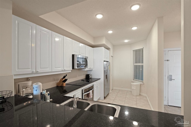 kitchen featuring white cabinetry, sink, stainless steel appliances, dark stone countertops, and light tile patterned floors