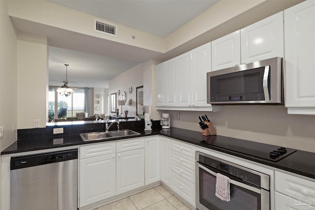 kitchen featuring stainless steel appliances, sink, light tile patterned floors, a chandelier, and white cabinetry