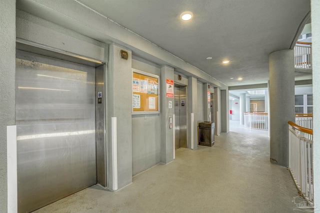 hall featuring a textured ceiling and elevator