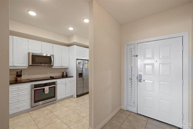 kitchen with white cabinets, light tile patterned floors, and appliances with stainless steel finishes