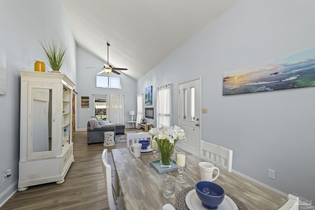 dining space featuring high vaulted ceiling, dark wood finished floors, baseboards, and a ceiling fan