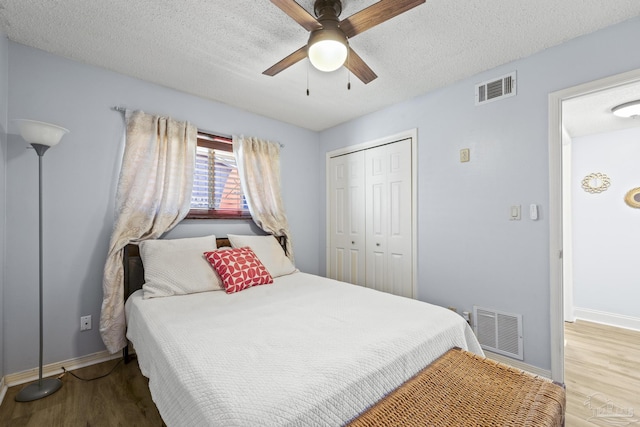 bedroom with a closet, wood finished floors, visible vents, and baseboards