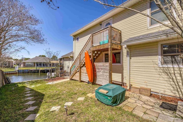 back of house with stairs, a yard, and a water view