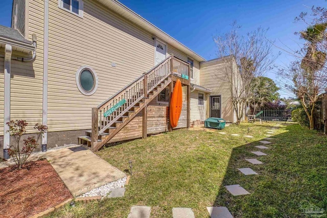 rear view of house featuring fence, stairway, and a yard