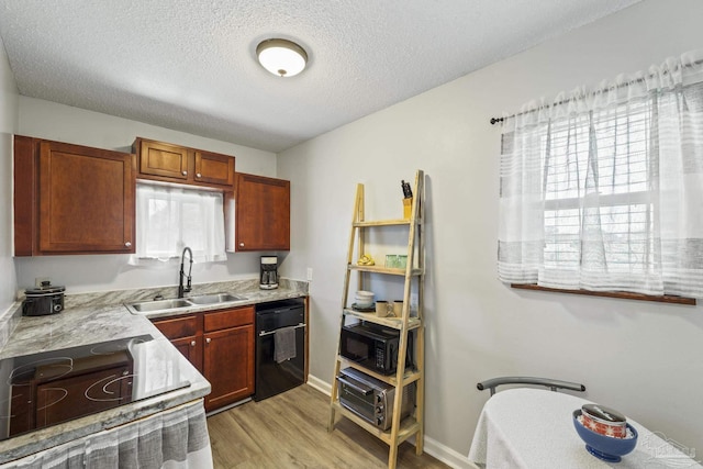 kitchen with baseboards, a textured ceiling, light wood-type flooring, black appliances, and a sink