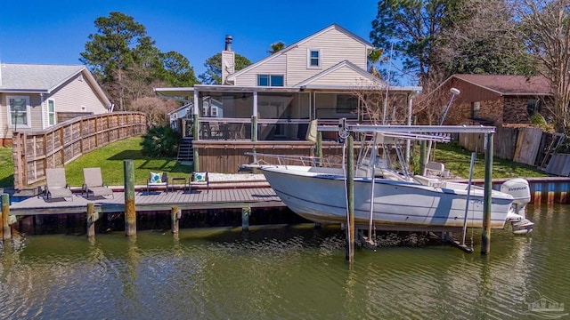 rear view of house featuring boat lift, a chimney, fence, and a deck with water view