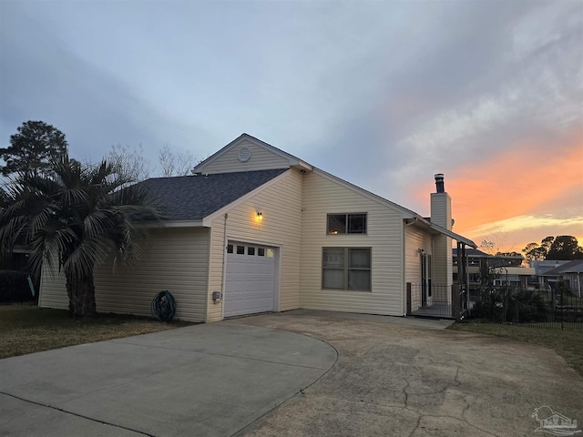 view of front of property featuring a garage, concrete driveway, a shingled roof, and a chimney