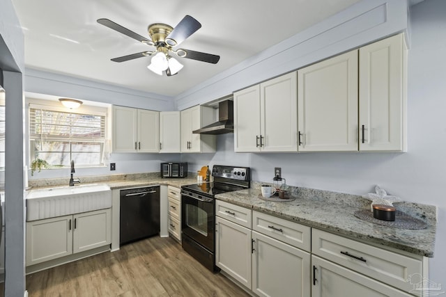 kitchen with light stone counters, wood finished floors, a sink, wall chimney range hood, and black appliances