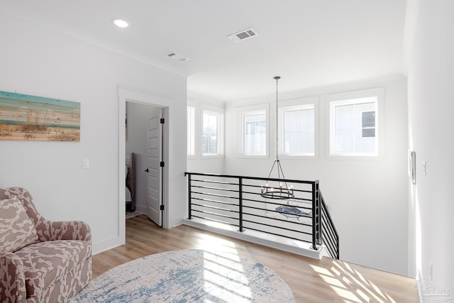 living area with a notable chandelier, light hardwood / wood-style floors, and ornamental molding