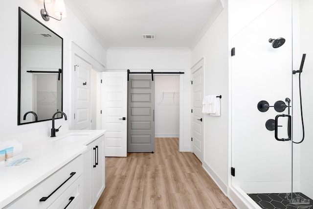 bathroom with hardwood / wood-style flooring, vanity, ornamental molding, and a shower with door