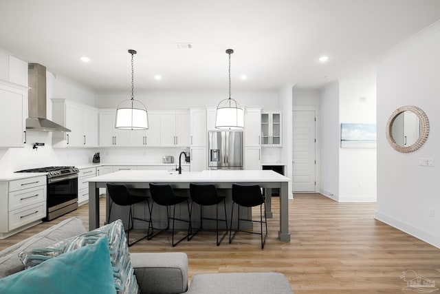 kitchen with white cabinets, appliances with stainless steel finishes, and wall chimney exhaust hood