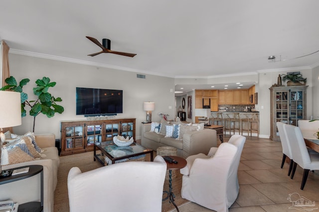 tiled living room with ornamental molding and ceiling fan