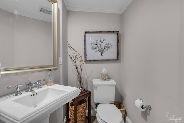 bathroom with crown molding, toilet, and sink