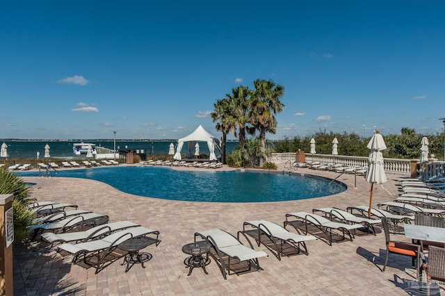 view of pool featuring a water view and a patio