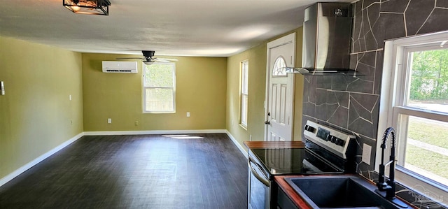 607 Hannah St, Pensacola, FL 32534 - kitchen with wall chimney exhaust hood, a ceiling fan, a wall mounted AC, dark wood-style floors, and stainless steel range with electric cooktop