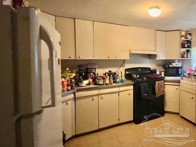 kitchen with black electric range oven, light tile patterned floors, and backsplash