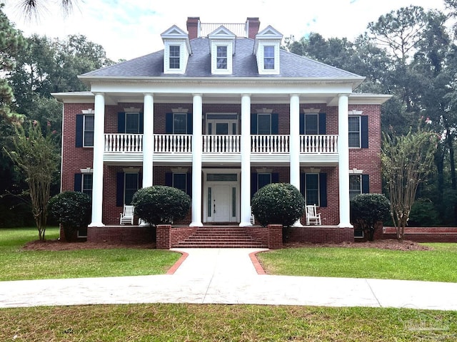 neoclassical home with a balcony and a front yard