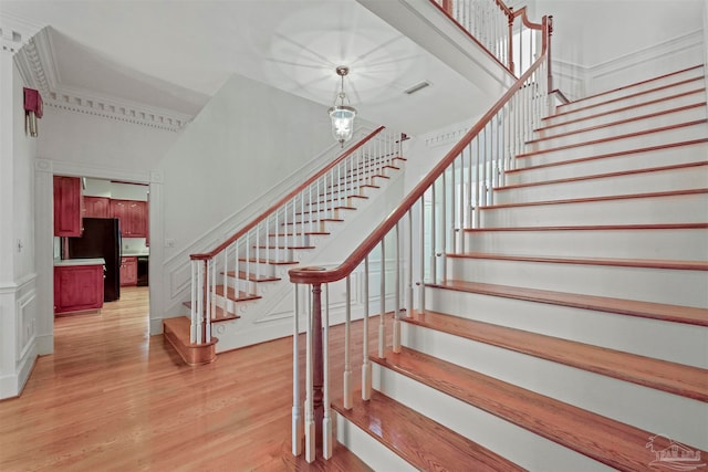 staircase featuring a towering ceiling, hardwood / wood-style floors, and a notable chandelier