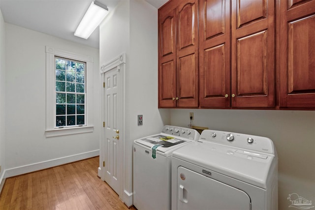 laundry area with cabinets, light hardwood / wood-style flooring, and washing machine and clothes dryer