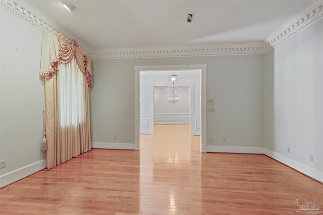 spare room featuring light hardwood / wood-style floors, ornamental molding, and a chandelier