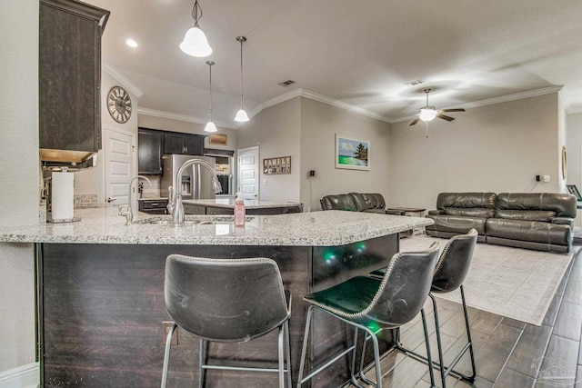 kitchen featuring hanging light fixtures, ornamental molding, a breakfast bar, dark hardwood / wood-style flooring, and ceiling fan