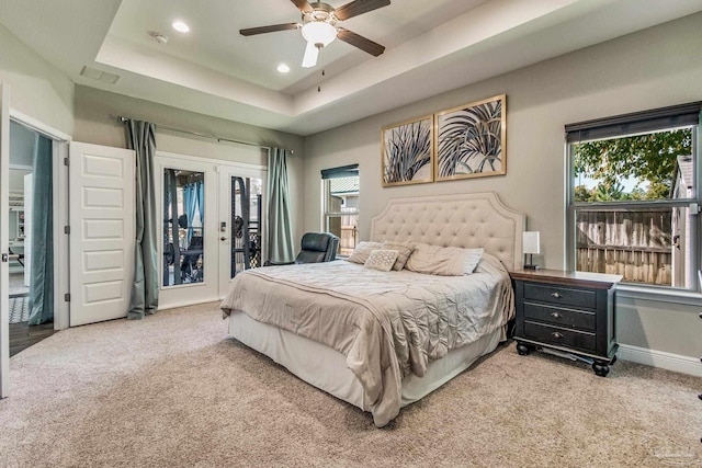 carpeted bedroom featuring a raised ceiling, access to outside, and ceiling fan