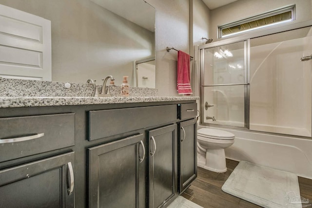 full bathroom with vanity, enclosed tub / shower combo, hardwood / wood-style flooring, and toilet