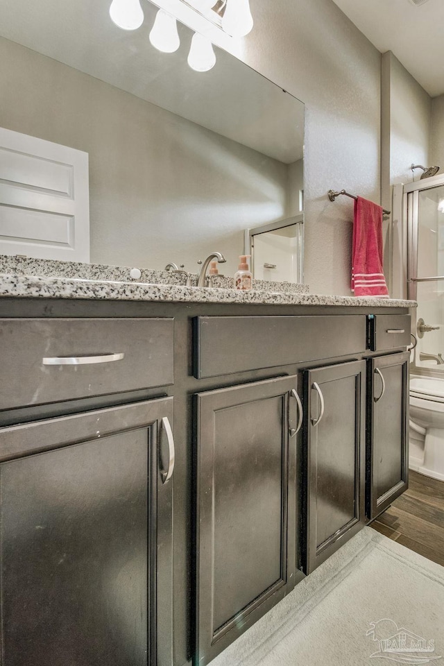 bathroom with vanity, toilet, hardwood / wood-style flooring, and walk in shower