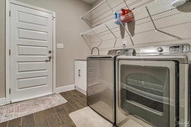 washroom featuring cabinets, washing machine and clothes dryer, and dark hardwood / wood-style flooring