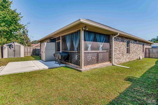 view of side of property featuring a patio area, a storage unit, a lawn, and a sunroom