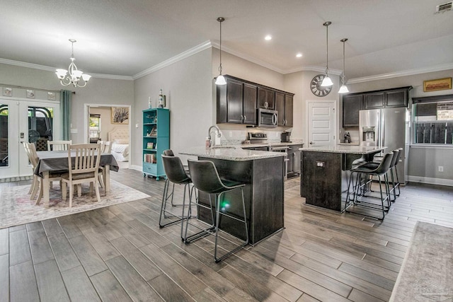 kitchen featuring a breakfast bar area, dark brown cabinets, hardwood / wood-style floors, pendant lighting, and appliances with stainless steel finishes