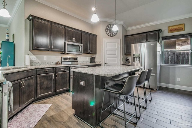 kitchen with hardwood / wood-style flooring, appliances with stainless steel finishes, sink, and decorative light fixtures