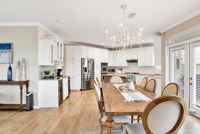 dining area featuring crown molding, a notable chandelier, wine cooler, and light wood-type flooring