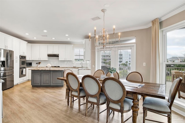 dining space featuring ornamental molding, a healthy amount of sunlight, a notable chandelier, and light hardwood / wood-style floors