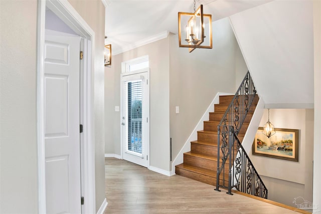 foyer entrance with wood-type flooring, a chandelier, and ornamental molding