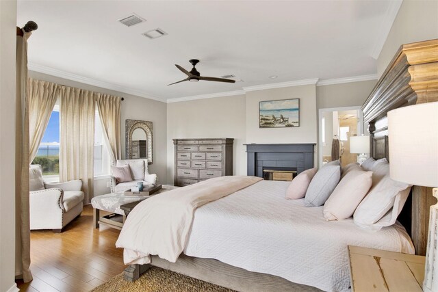 bedroom with ceiling fan, ornamental molding, wood-type flooring, and multiple windows