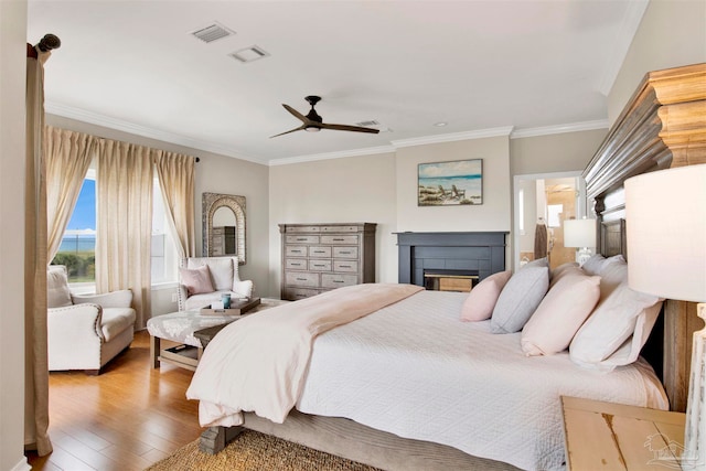 bedroom featuring ceiling fan, hardwood / wood-style flooring, a fireplace, and crown molding