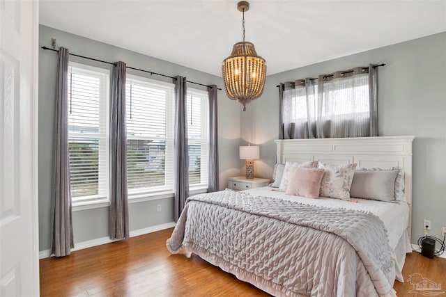 bedroom with multiple windows, hardwood / wood-style flooring, and a chandelier