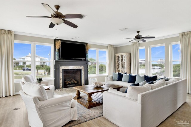 living room featuring a fireplace, a wealth of natural light, ceiling fan, and light hardwood / wood-style floors