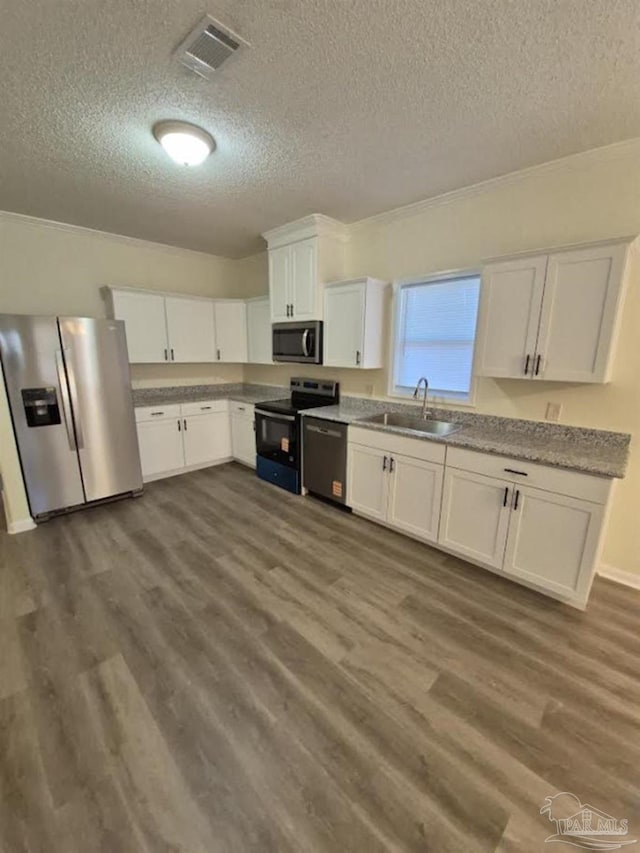 2008 Augusta Ave, Pensacola, FL 32507 - kitchen featuring appliances with stainless steel finishes, a textured ceiling, a sink, white cabinets, and dark wood-style flooring