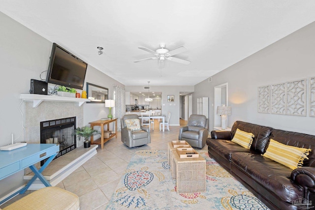 living room featuring light tile patterned floors, a tile fireplace, and ceiling fan