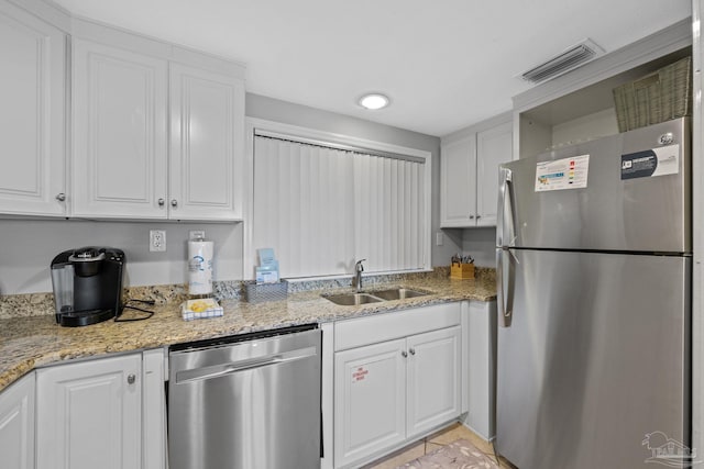 kitchen featuring light stone counters, visible vents, a sink, white cabinets, and appliances with stainless steel finishes