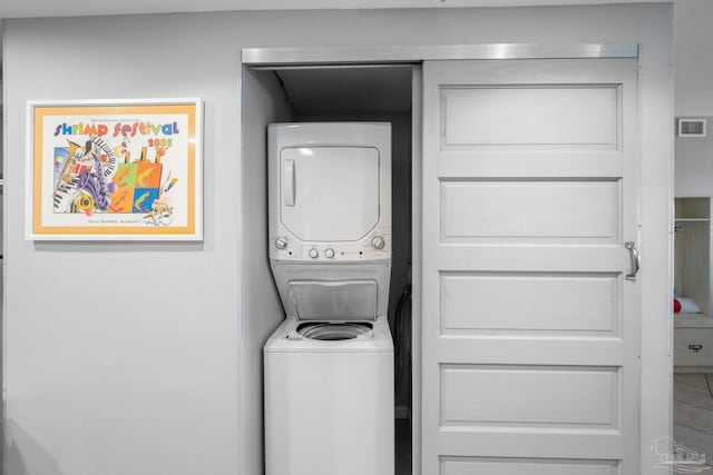 laundry room with visible vents, stacked washer and clothes dryer, and laundry area